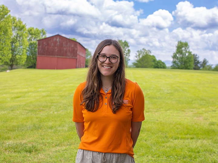 Headshot of Alex Gibson wearing a Herbert polo in a field with a red barn in the background.
