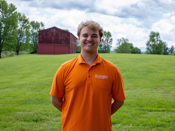 Headshot of Jim Jenkins wearing a Herbert polo in a field with a red barn in the background.
