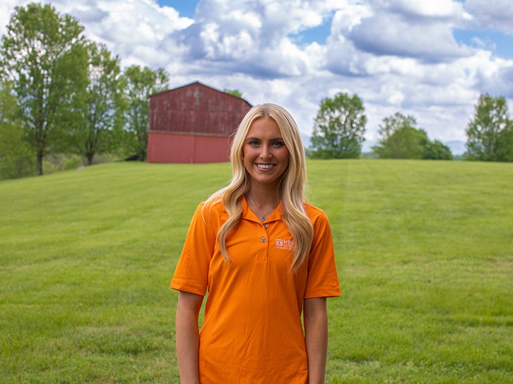 Headshot of Livvy Lightholder wearing a Herbert polo in a field with a red barn in the background.