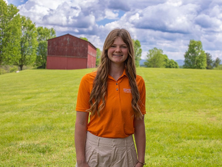 Headshot of Livy Muntz wearing a Herbert polo in a field with a red barn in the background.
