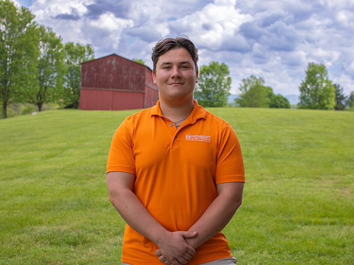Headshot of Tim Conlon wearing a Herbert polo in a field with a red barn in the background.
