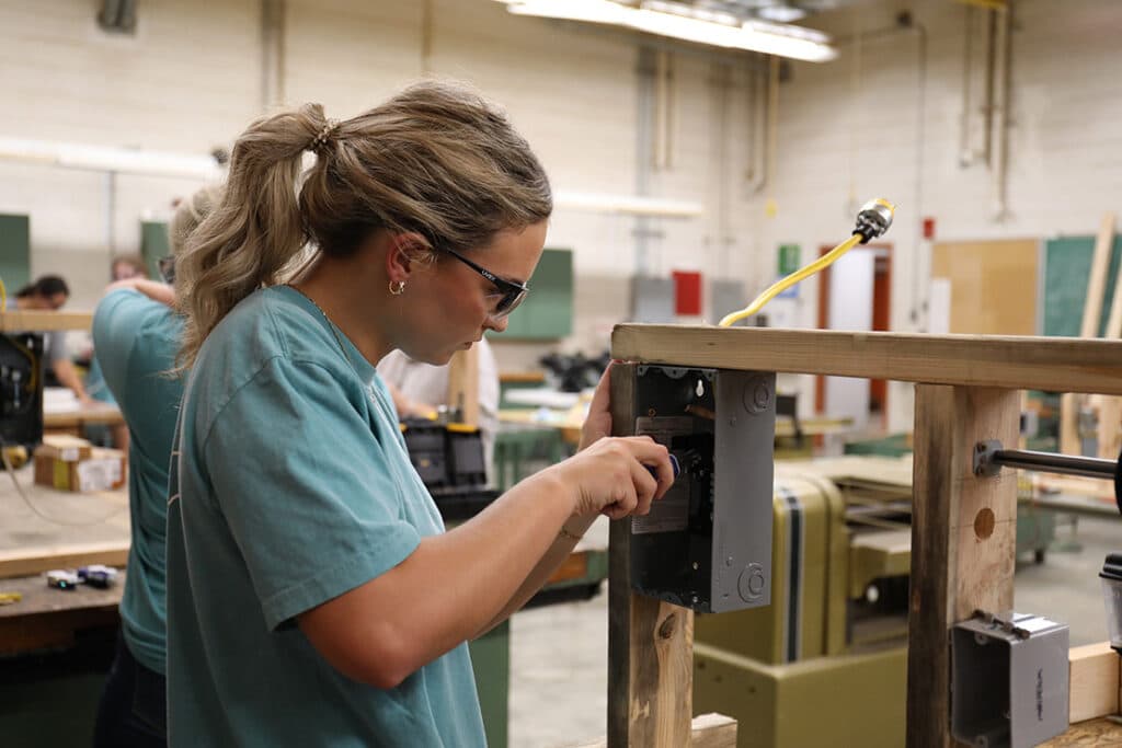 A student wearing protective glasses and working on a project in a shop class.