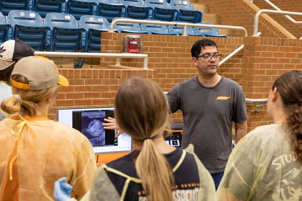 A professor pointing to the screen of an animal ultrasound in front of a group of animal science students.