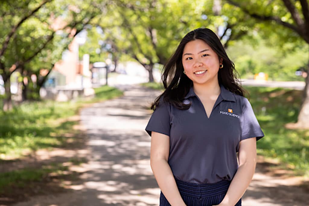 Headshot of Ploy Wong wearing a gray food science polo outside with trees in the background.