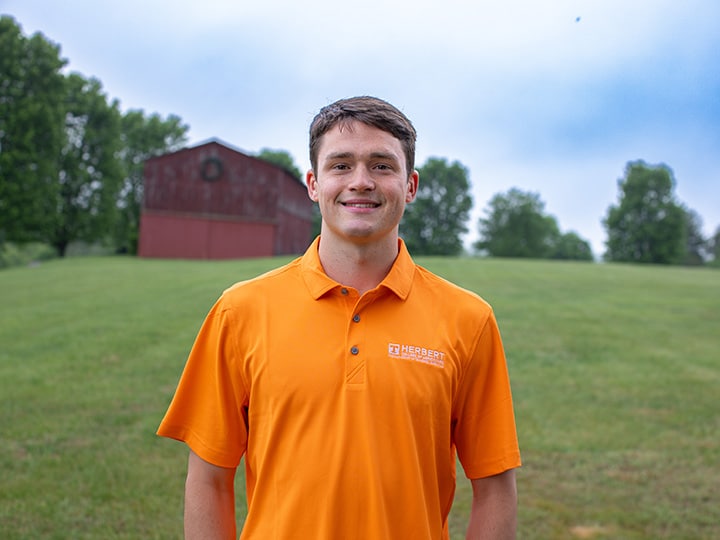 Headshot of Jack Bukovitz wearing a Herbert polo in a field with a red barn in the background.