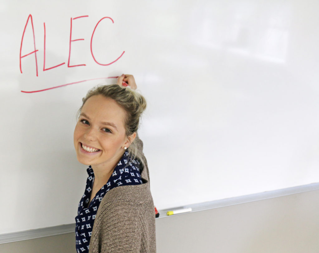 Woman writing ALEC on whiteboard