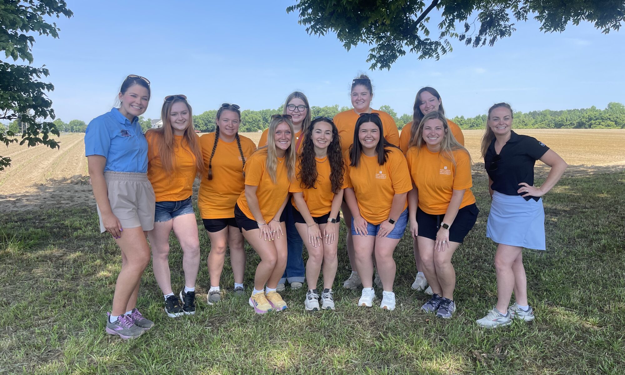 Group photo of Collegiate Farm Bureau, 4-H, and FFA members in an outdoor setting wearing orange shirts